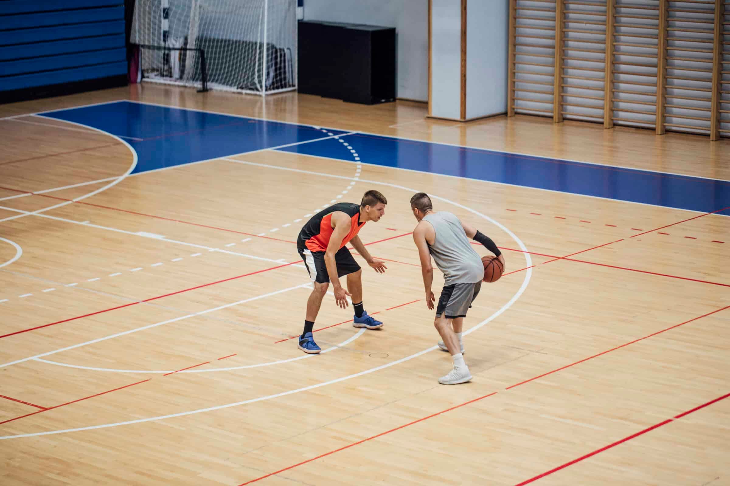 Two Young Athletes Playing Basketball in a School Gymnasium (Copy Space)