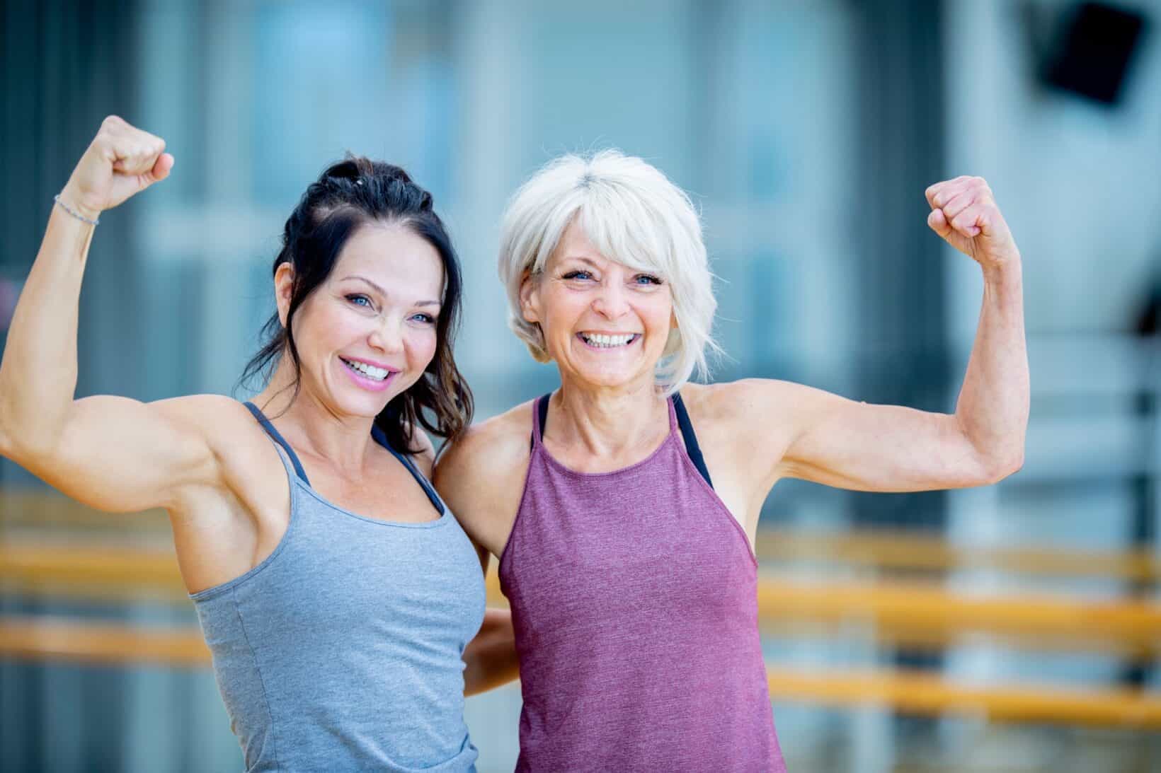 Two women proudly making a muscle and smiling