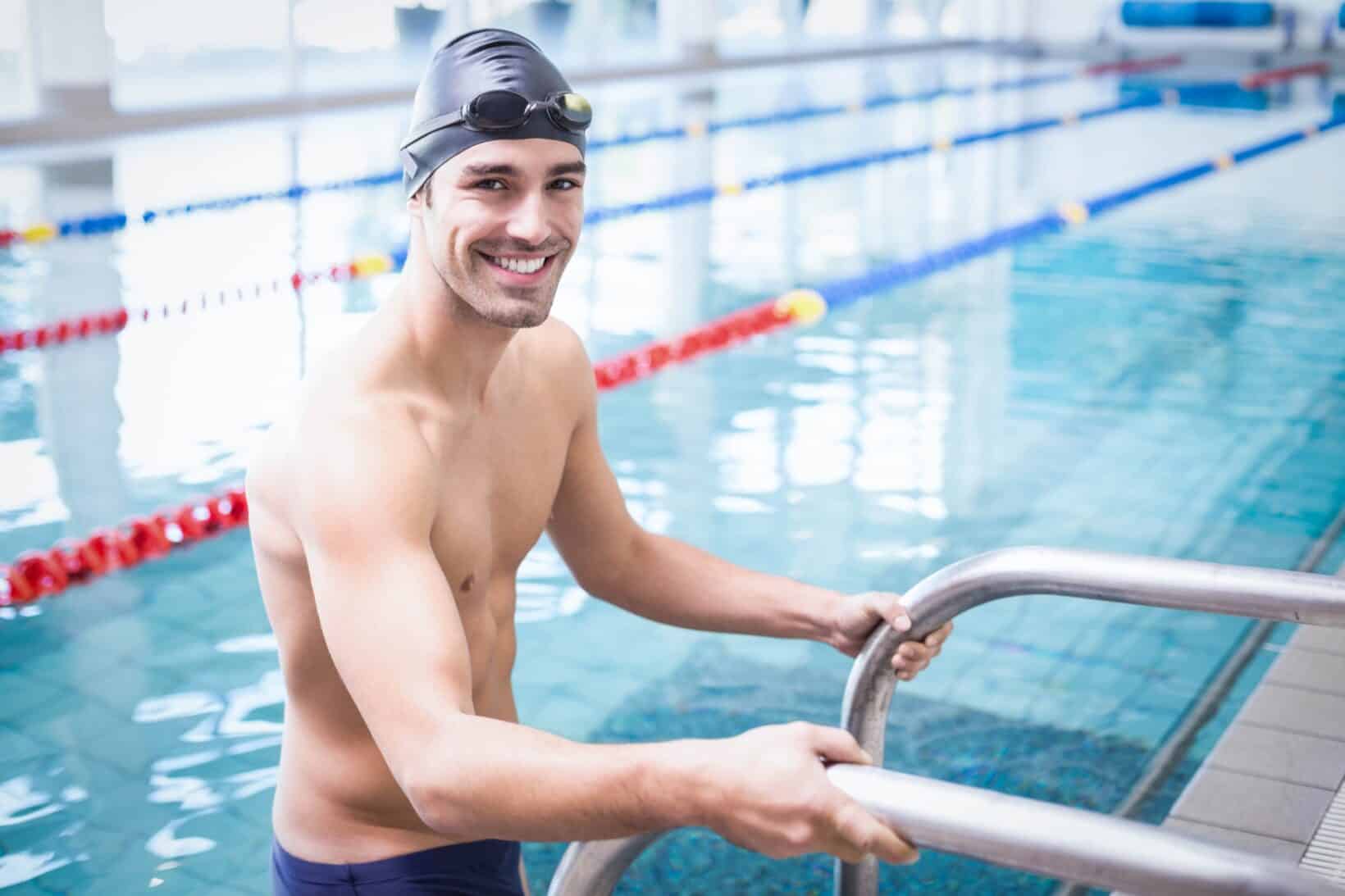 Male swimmer smiling while getting out of a pool